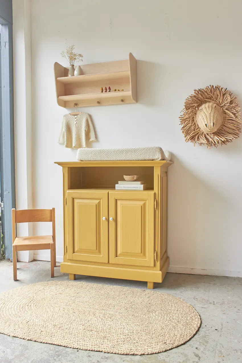 a yellow cabinet with a cushion on top and a chair and a straw hat on the wall